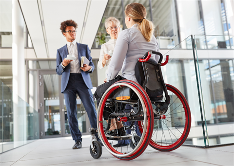 Image of 3 people in an office setting one of them is a wheelchair user