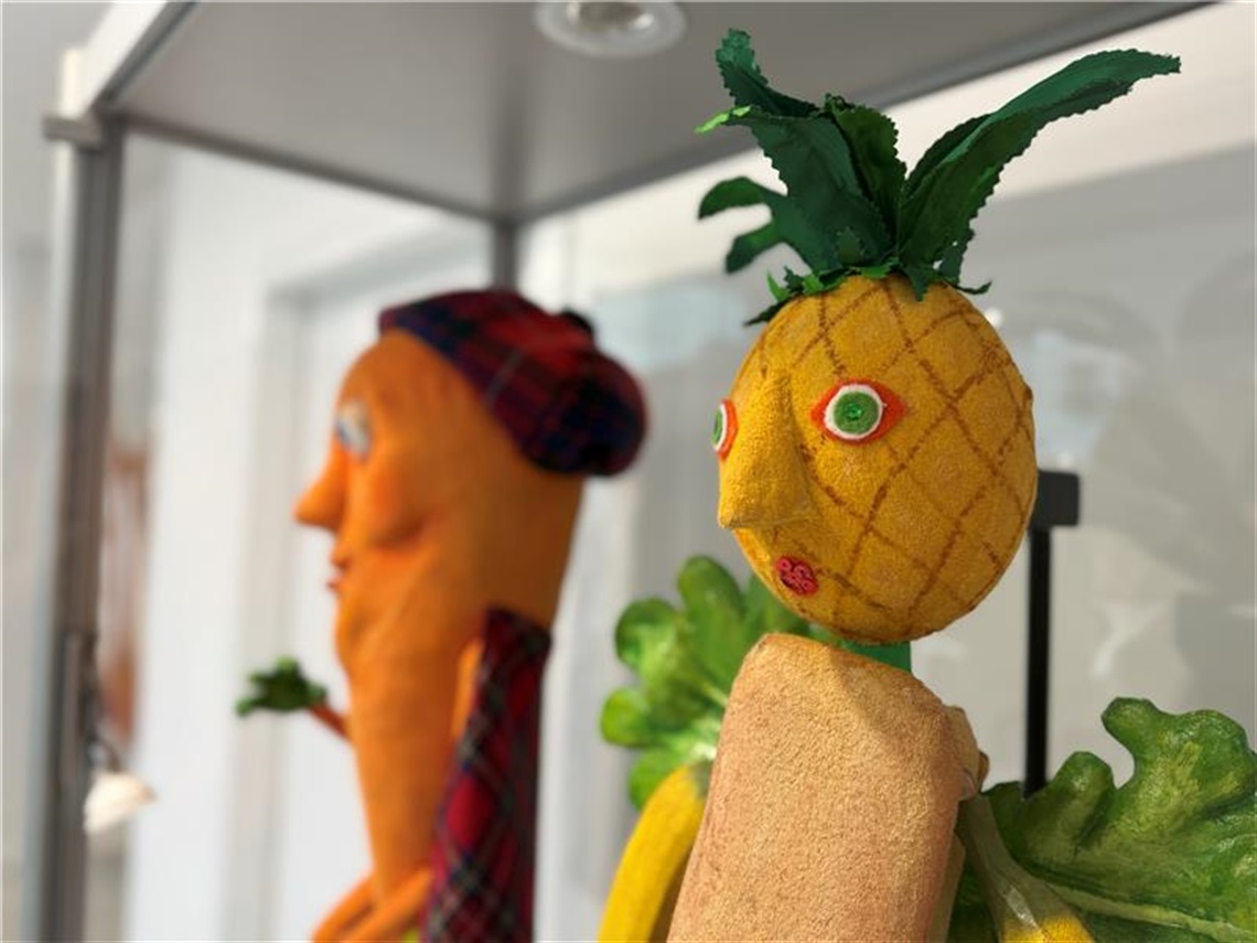 Carrot in a kilt puppet and tropical fruit puppet with a pineapple head and banana arms close up