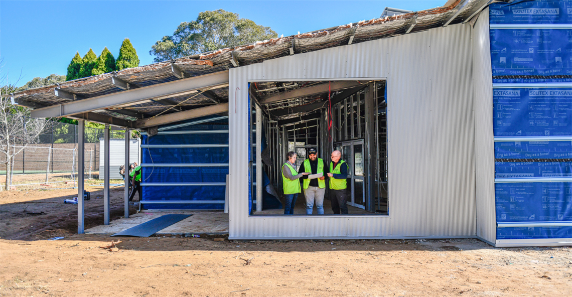 Picture of 3 people standing inside the partially constructed building