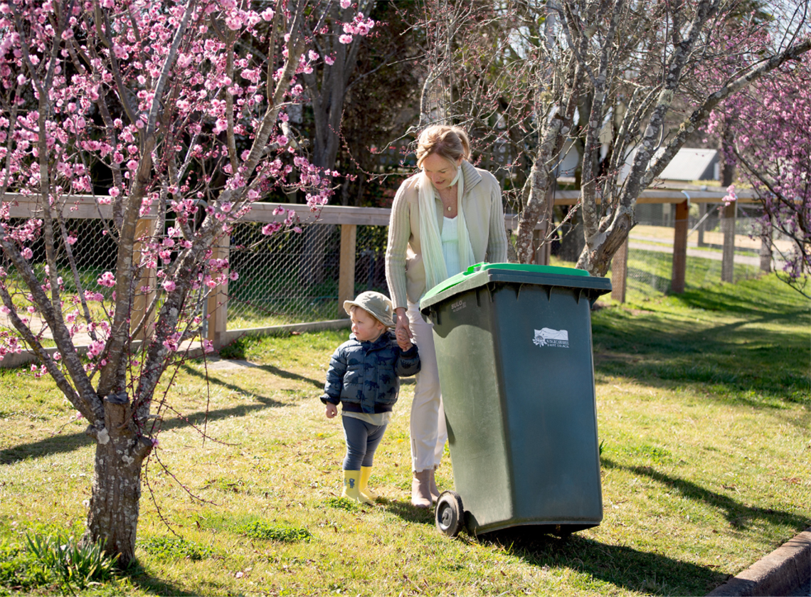 Woman taking kerbside waste bin out with child