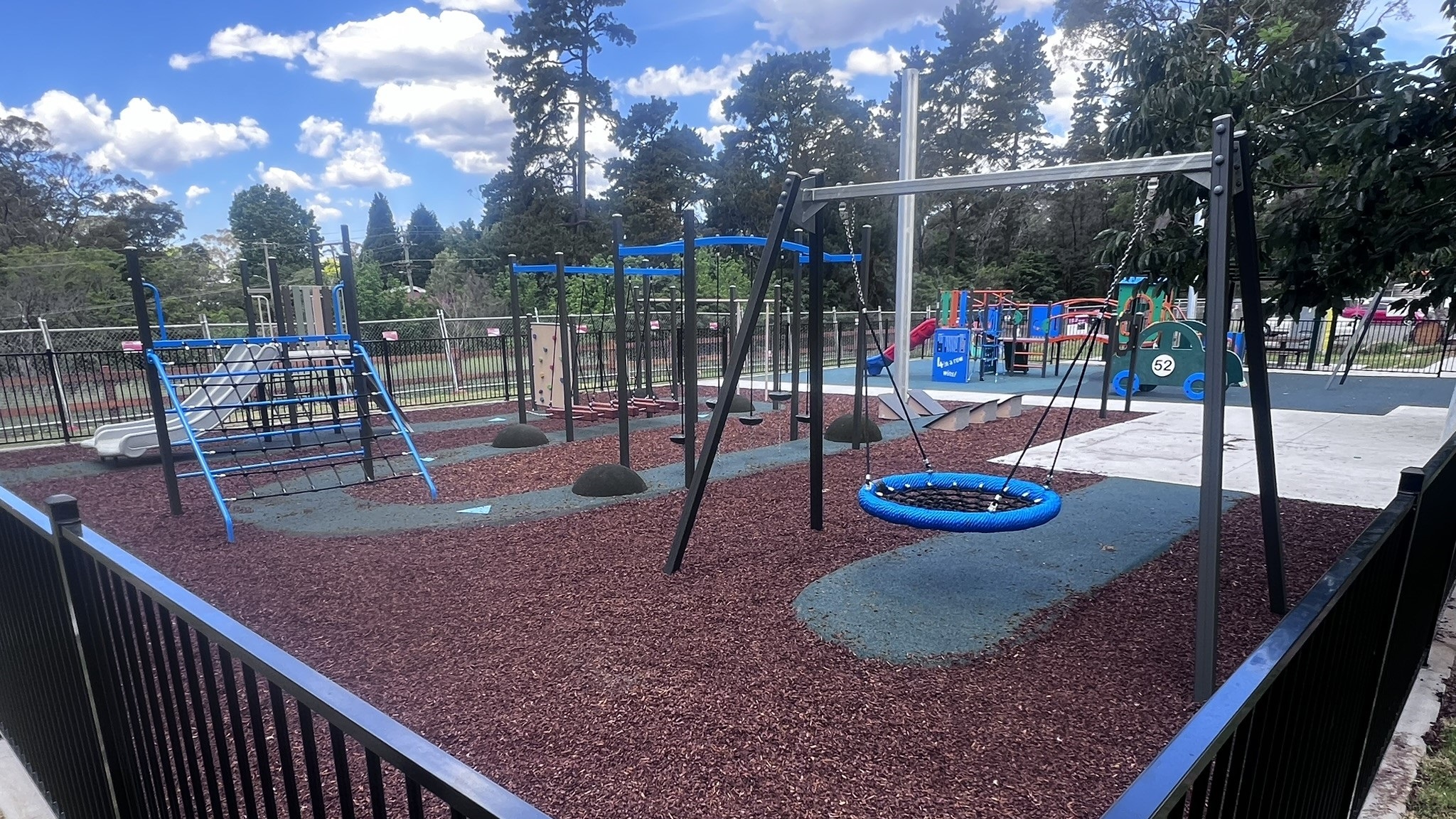 Hill Top Park playground featuring nest swing, climbing frame and more equipment in background