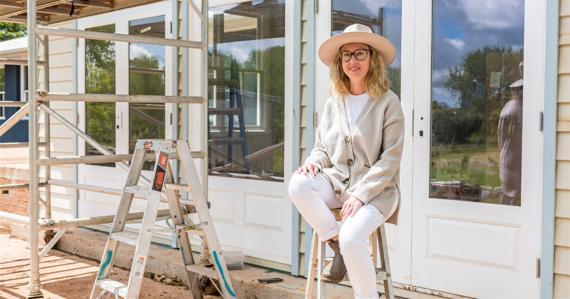 Lady relaxing on stool outside house under construction