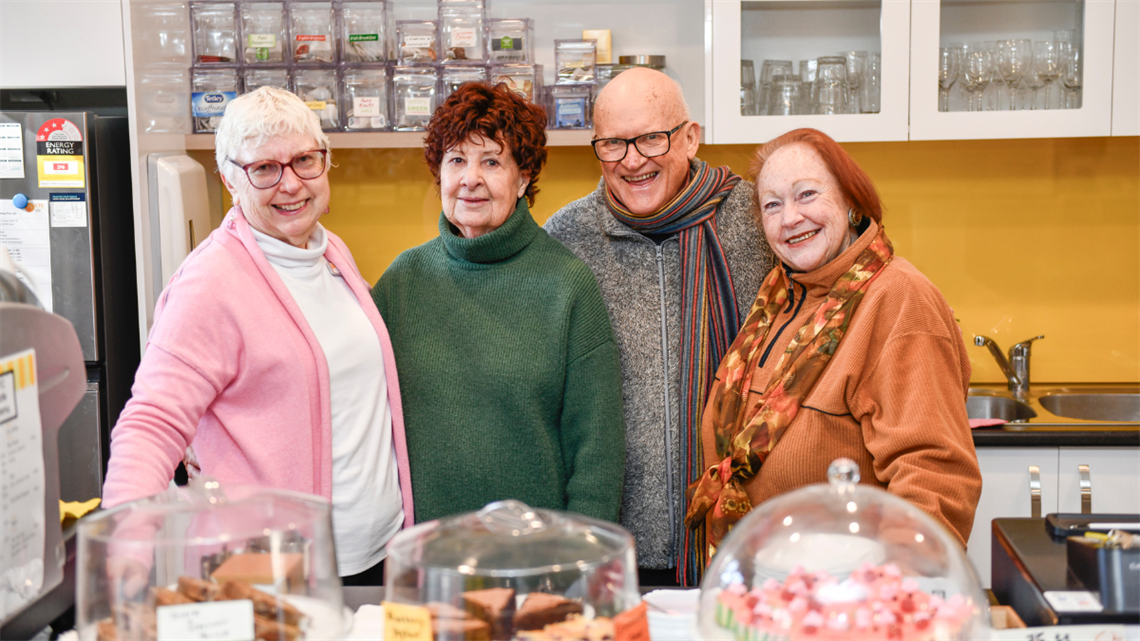 Volunteers standing behind the counter with cakes and biscuits in front of them