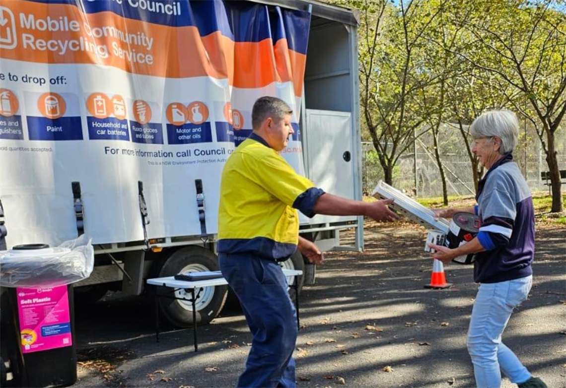 Lady handing recycling to council worker with recycling van