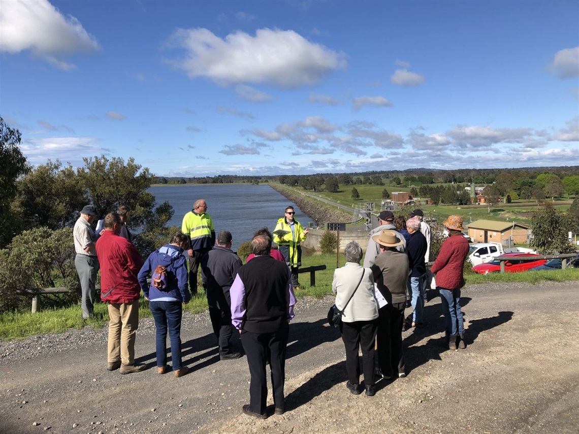 People standing next to a reservoir listening to tour guide