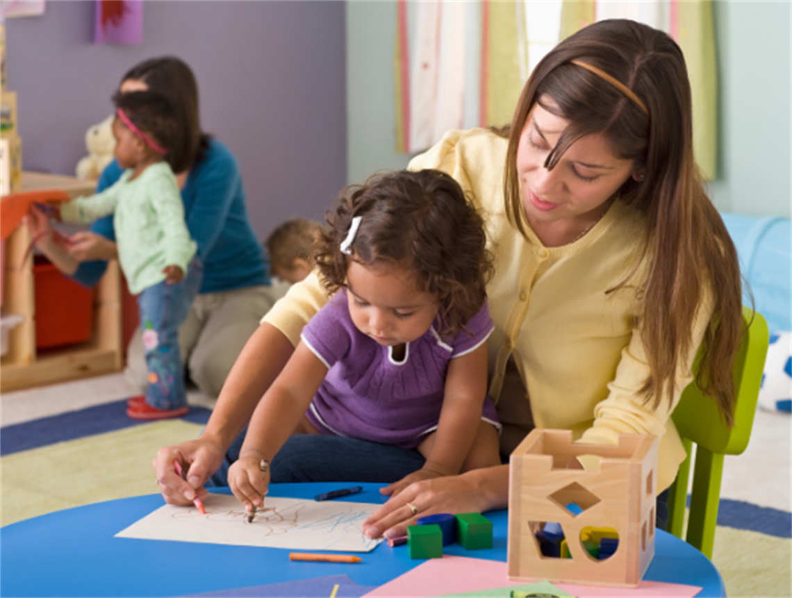 Teacher helping young child to draw