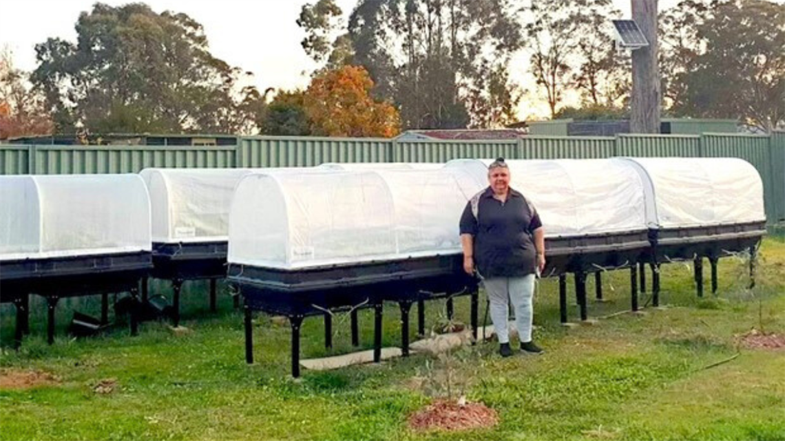 Aunty Marie standing next to the planting pods