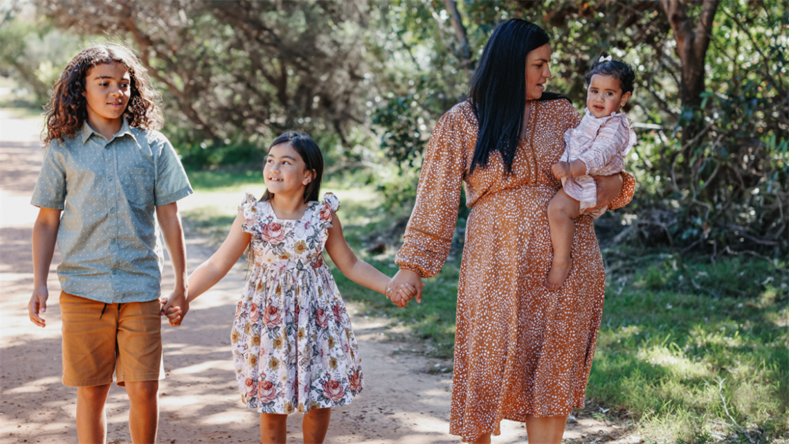 Mum and 3 kids walking along the road holding hands