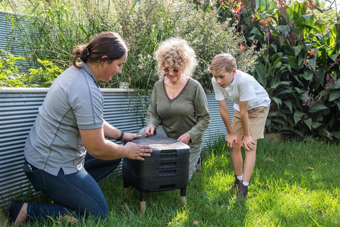 Somone showing a lady and her grandson how to compost