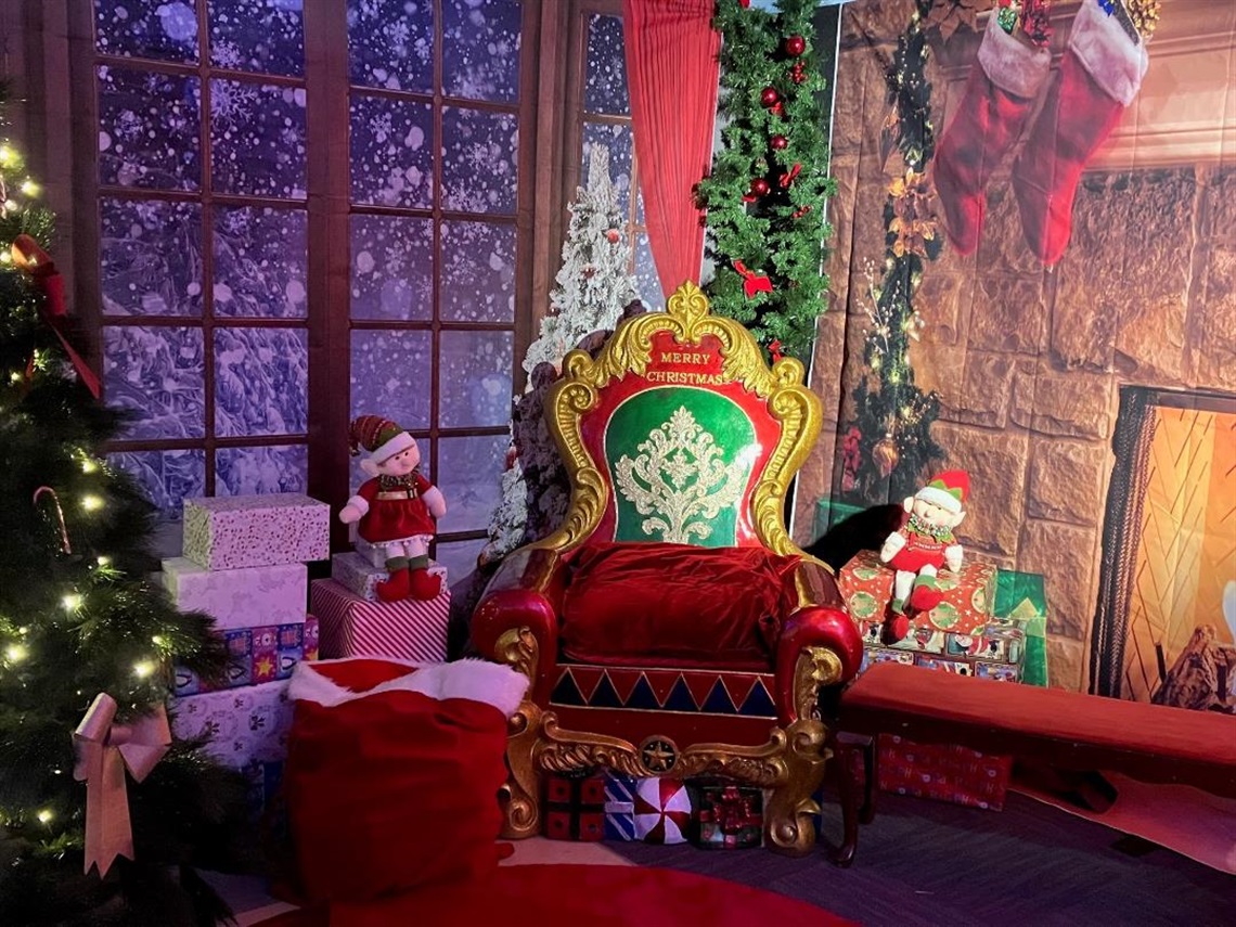 Santa's chair surrounded by presents, christmas tree and elf dolls in Santa's grotto 