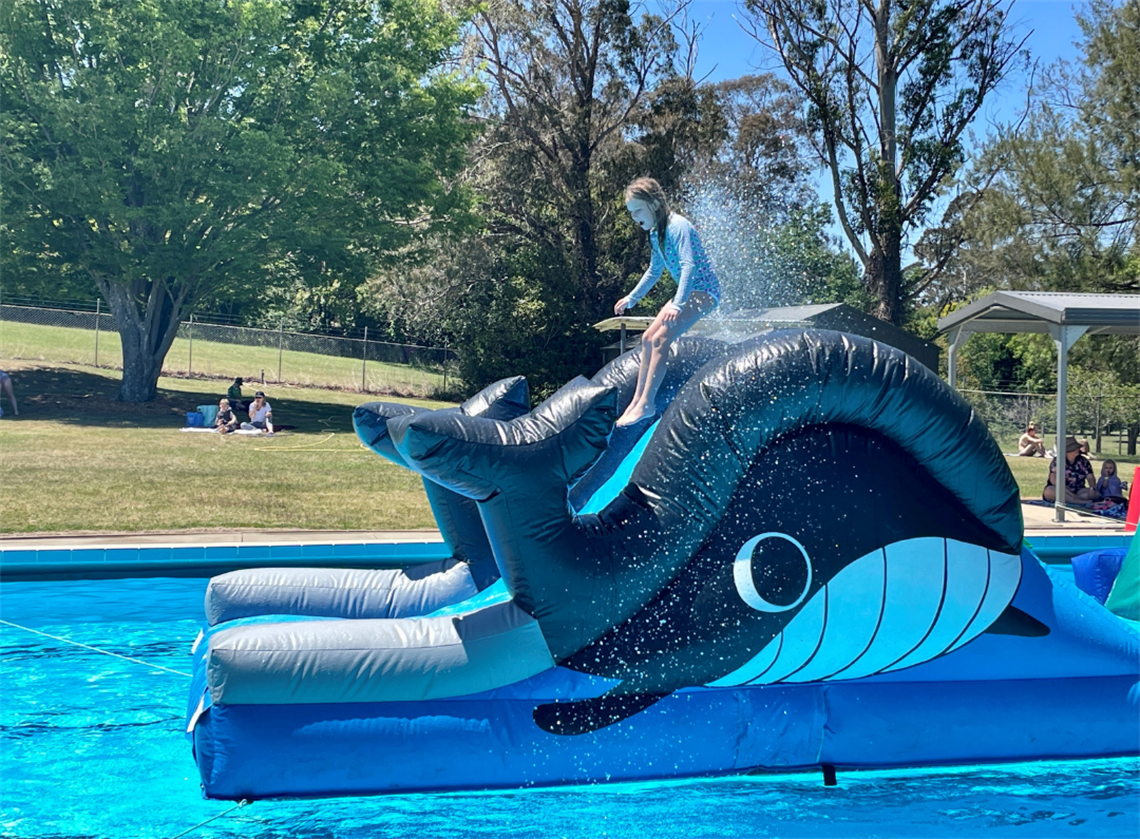 Girl jumps down pool inflatable whale slide