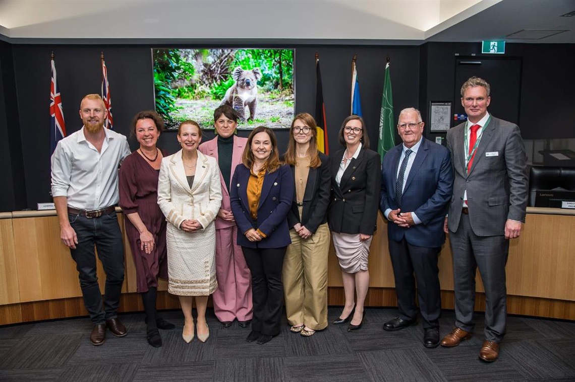 Group photo of all nine recently sworn in councillors including Mayor and Deputy Mayor stand in Council Chambers smiling at camera 