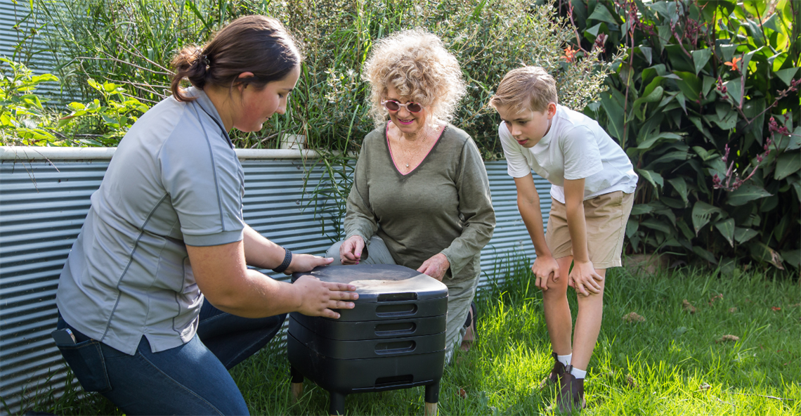 Picture of RRC staff teaching a lady and young boy about worm farming