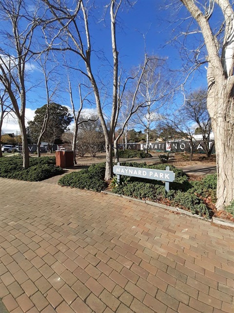 Path with trees and garden bed with sign with Maynard Park